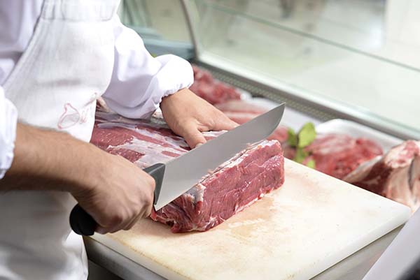 un boucher découpe la viande